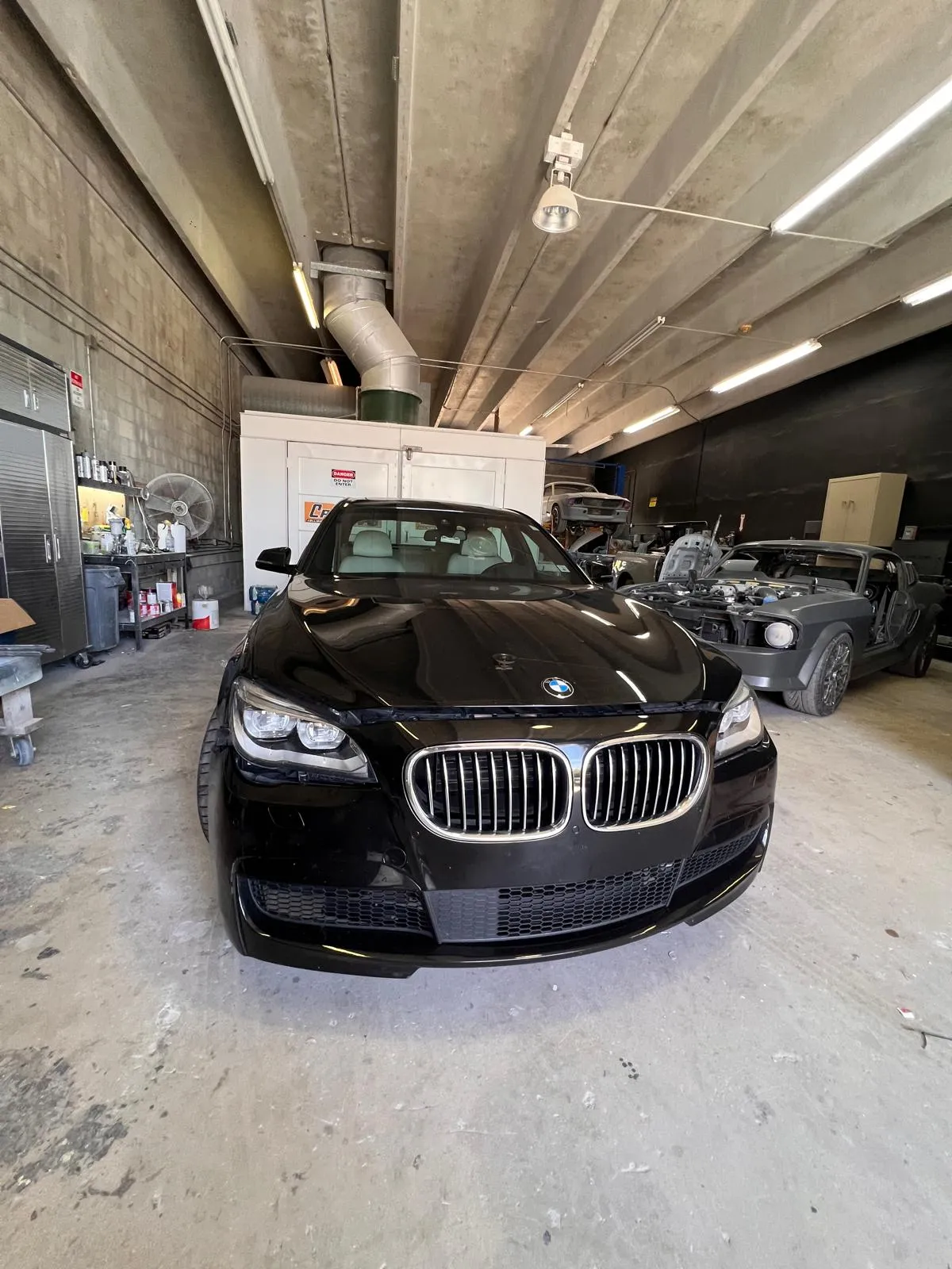 Black BMW 7 Series inside the Craft Collision body shop in Lake Worth Beach