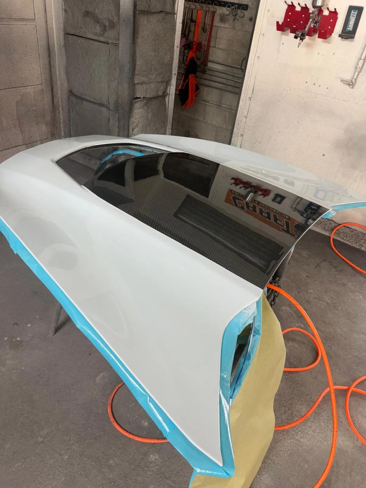 Painted body panel with an exposed carbon fiber insert, masked and prepped in the shop
