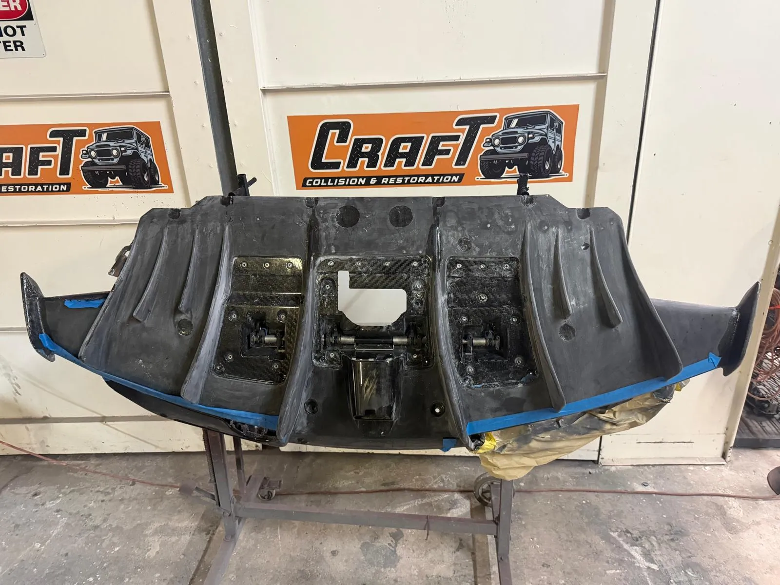 Carbon fiber diffuser on a stand under the Craft Collision sign in Lake Worth Beach