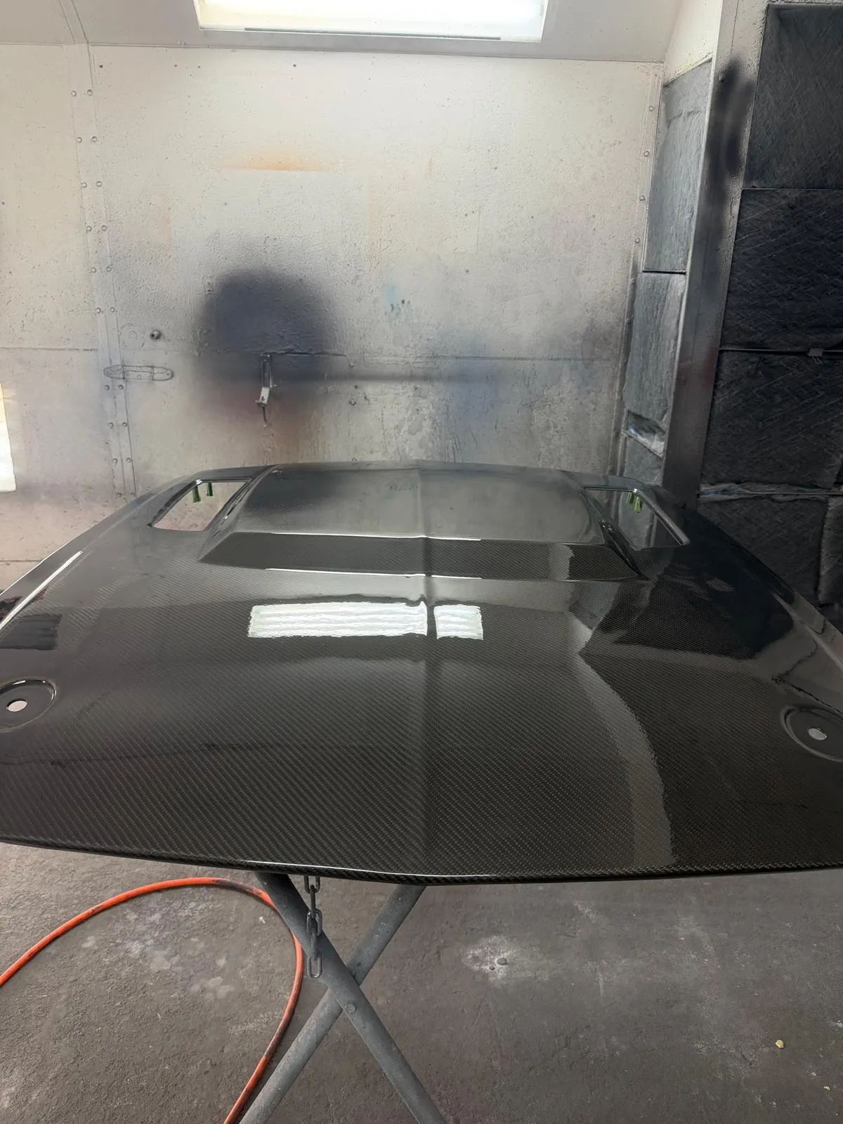Finished carbon fiber hood on a stand after clear coat at Craft Collision