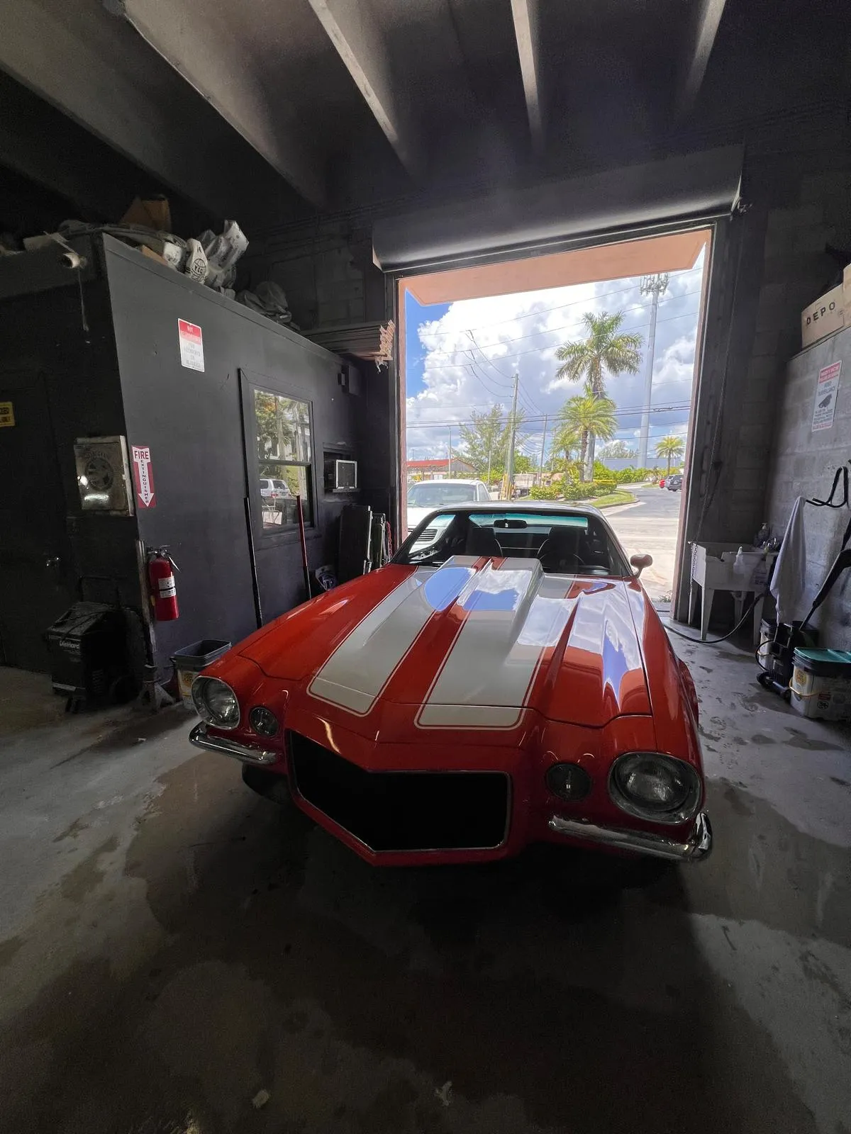 Red classic Chevrolet Corvette with white stripes in the doorway of the Craft Collision shop