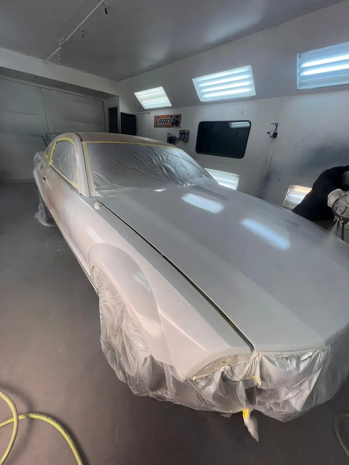 Silver classic Mustang fastback masked and covered inside the paint booth