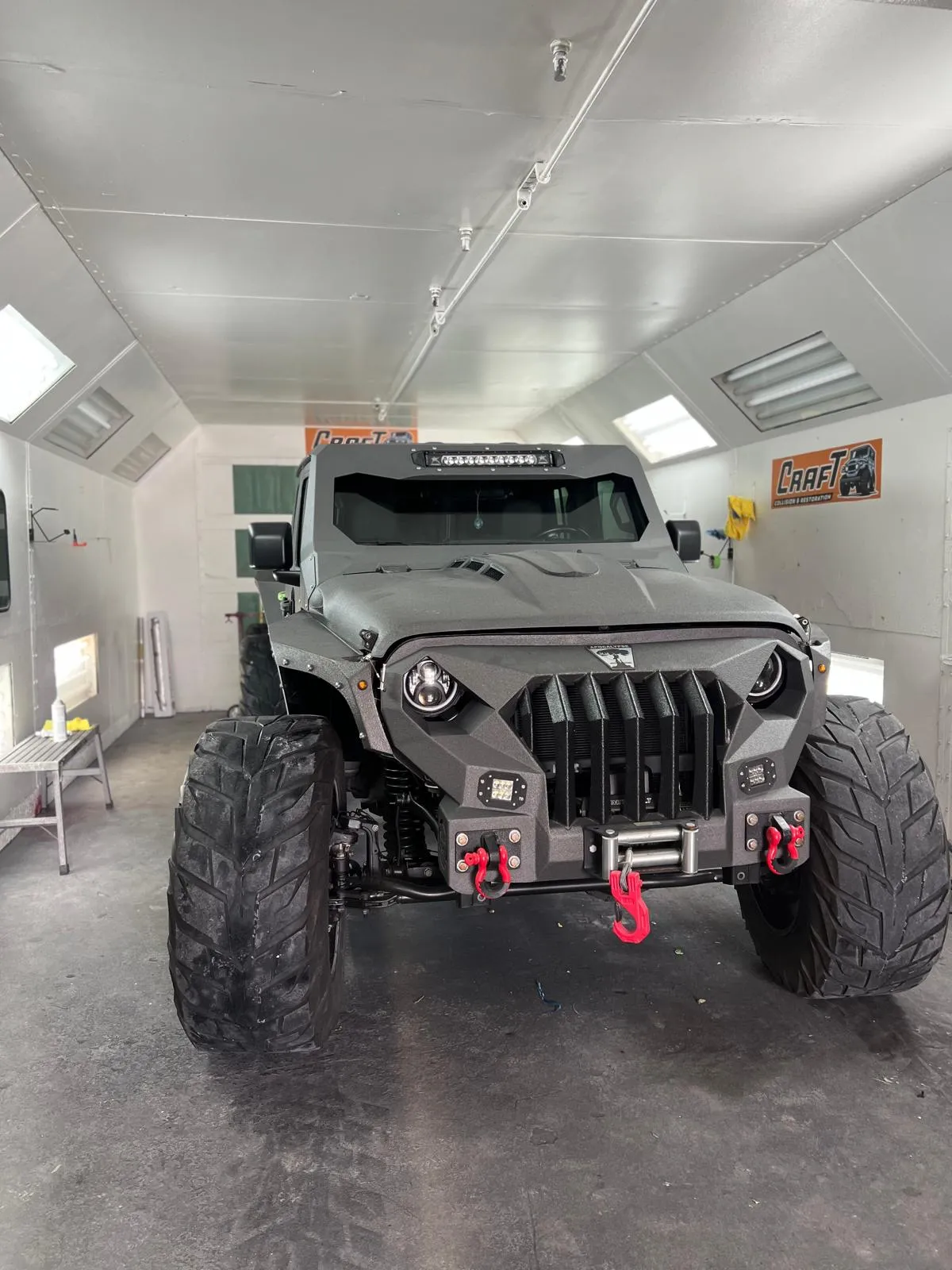 Custom lifted Jeep Wrangler in grey inside the Craft Collision paint booth