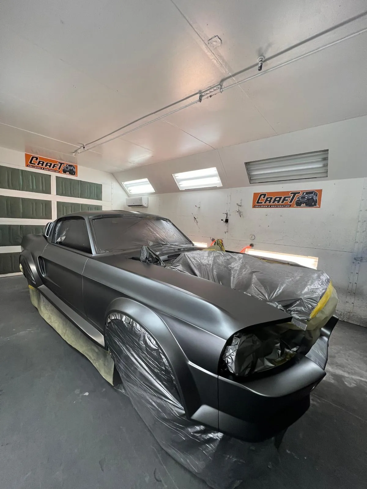 Custom Mustang fastback in matte grey with dark stripes inside the paint booth