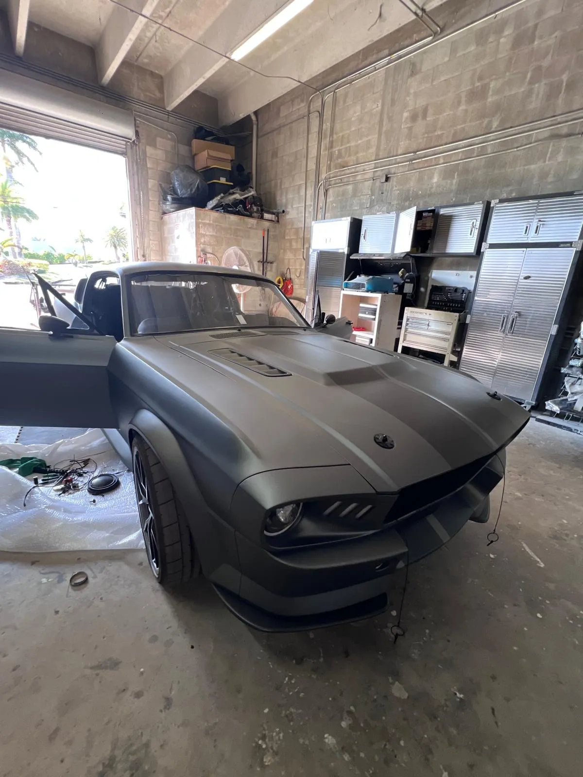 Custom matte grey Mustang fastback build parked inside the Craft Collision shop
