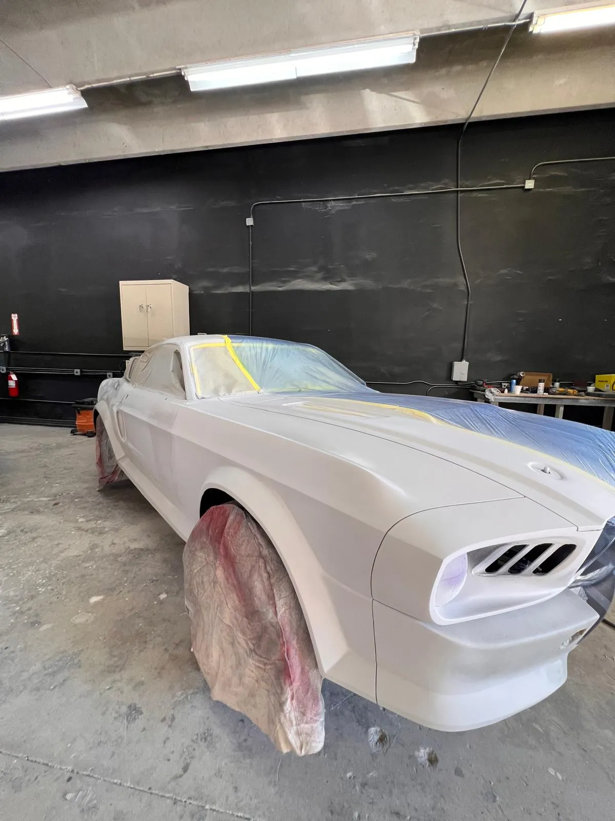 Custom 1967 Mustang fastback build in white primer inside the Craft Collision shop