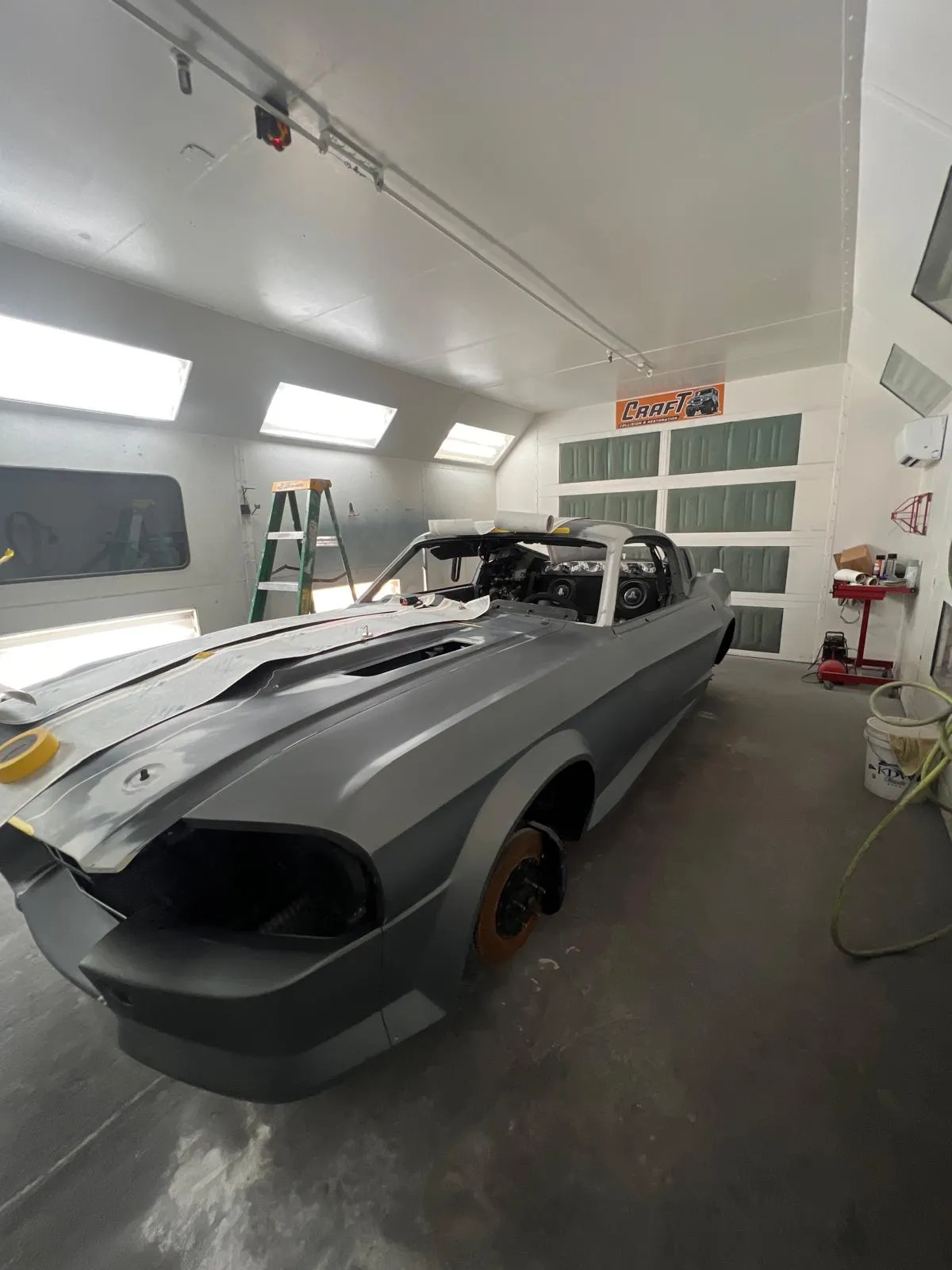 Custom Mustang fastback in matte grey inside the Craft Collision paint booth