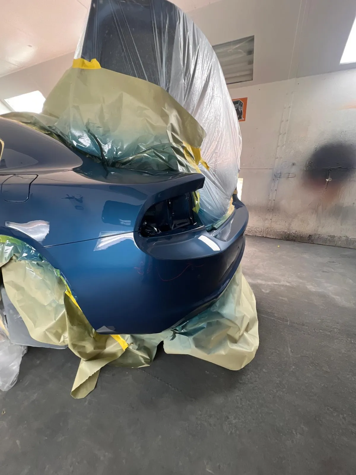 Blue Dodge Charger with the rear quarter and trunk masked inside the booth