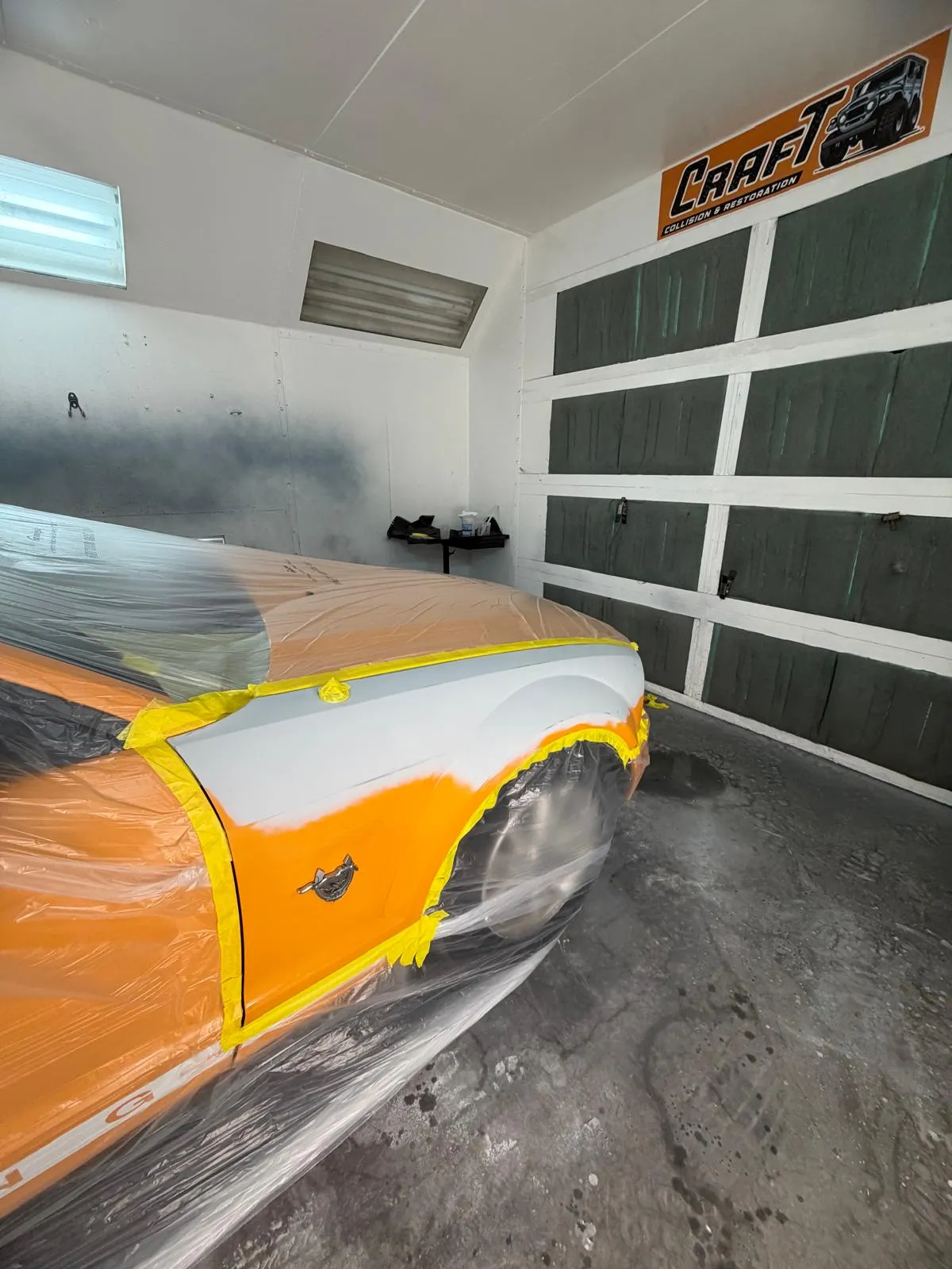 Orange Mustang with a primed fender masked off before the color coat goes on