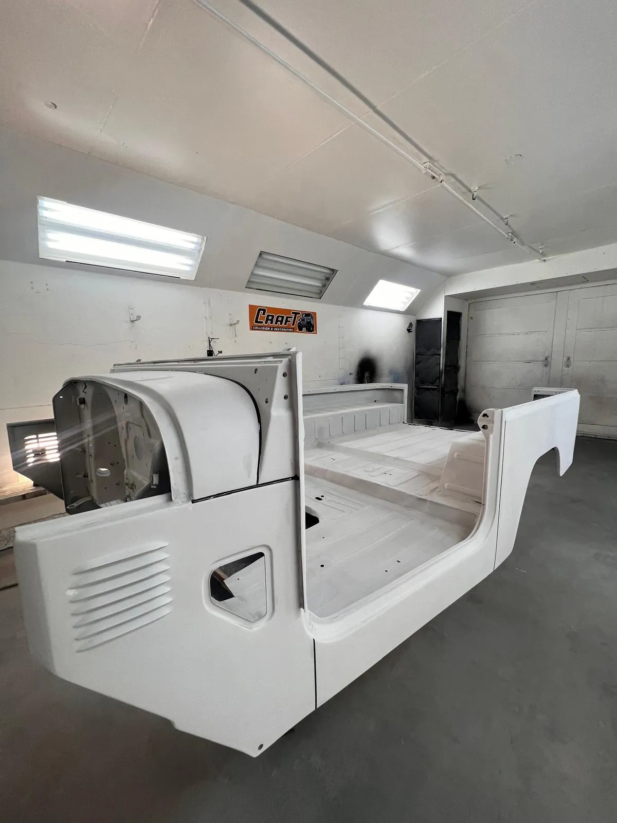 Toyota FJ40 body tub in primer inside the Craft Collision paint booth