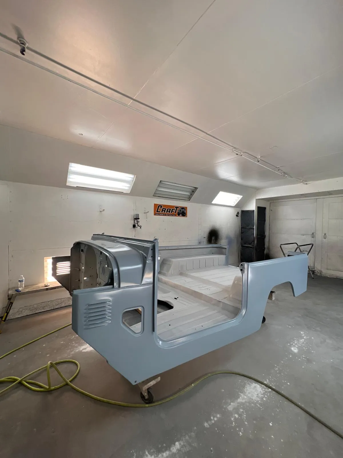 Toyota FJ40 body tub painted in classic blue inside the paint booth