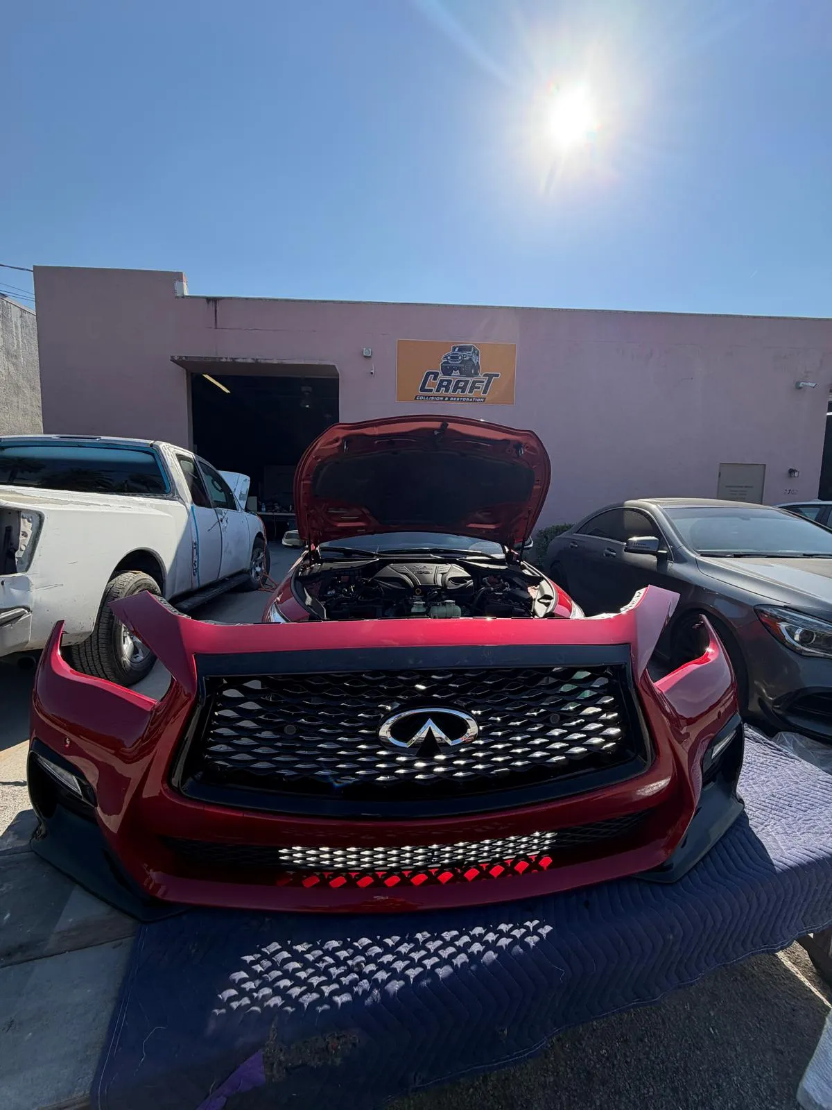 Red Infiniti with the front end fully disassembled in the yard at Craft Collision