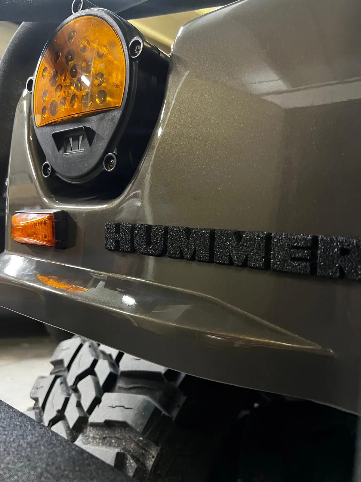 Close-up of a Hummer H1 front fender and badge after respray