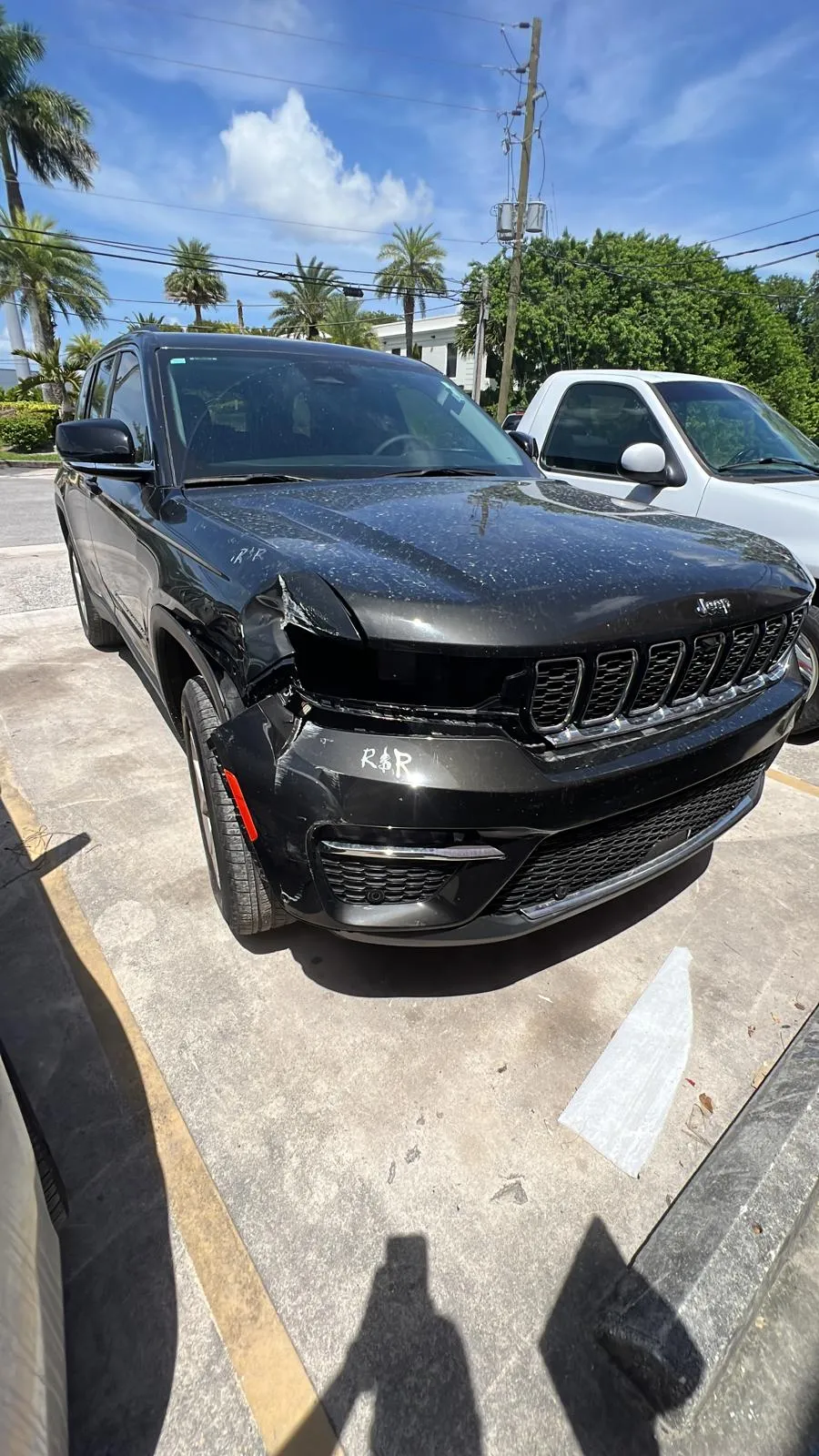 Black Jeep Grand Cherokee with a crushed front bumper and damaged headlight before repair