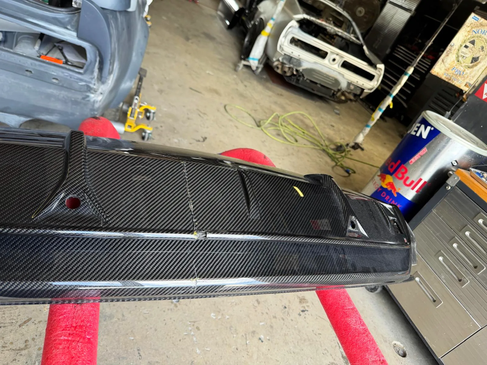 Damaged Lamborghini carbon fiber rear bumper being assessed on stands in the Craft Collision shop