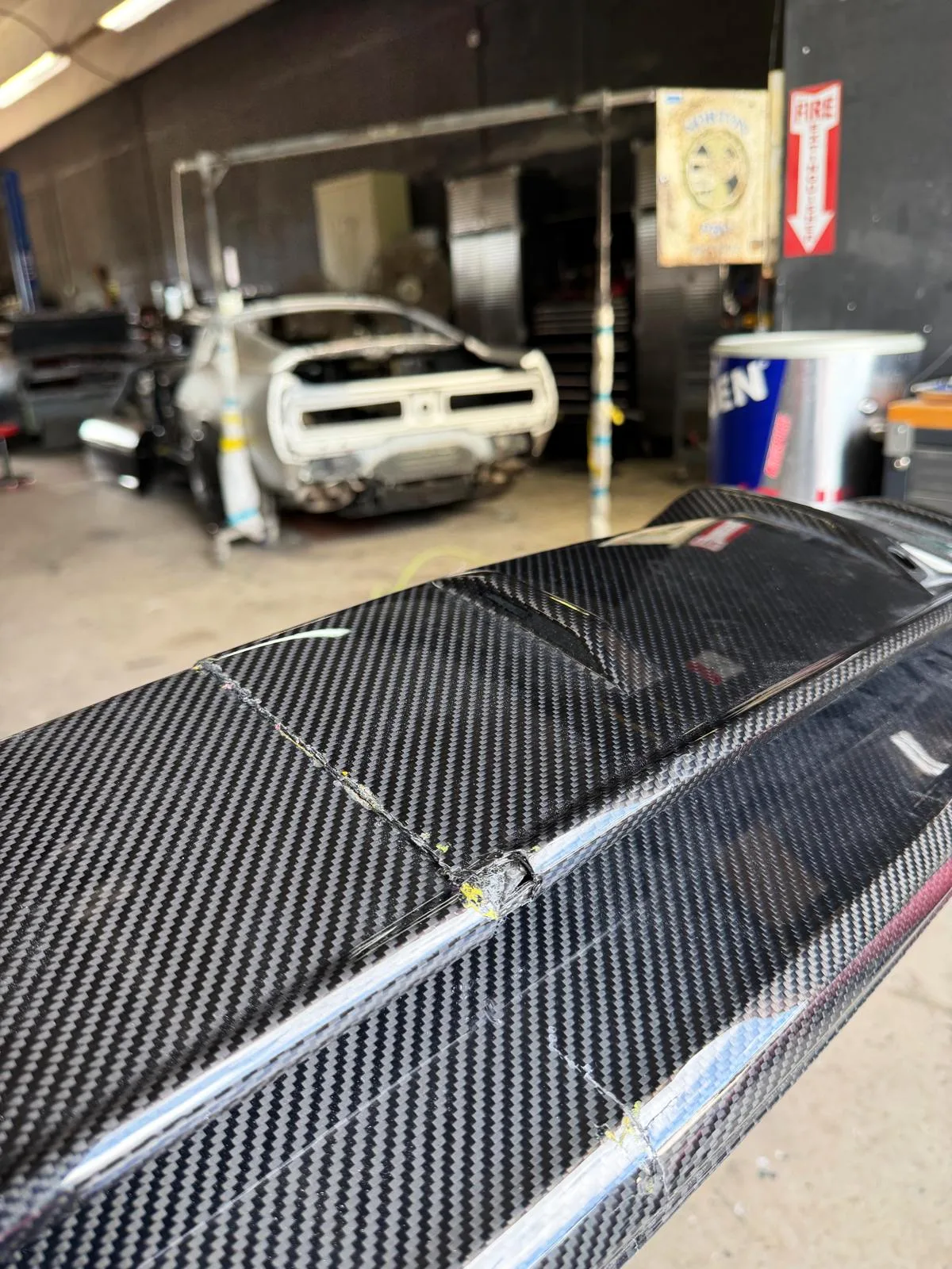 Close-up of the crack and lifted fibers on a damaged Lamborghini carbon fiber rear bumper before repair