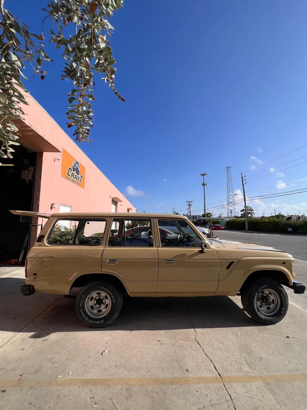 Restored tan Toyota Land Cruiser FJ60 outside Craft Collision in Lake Worth Beach