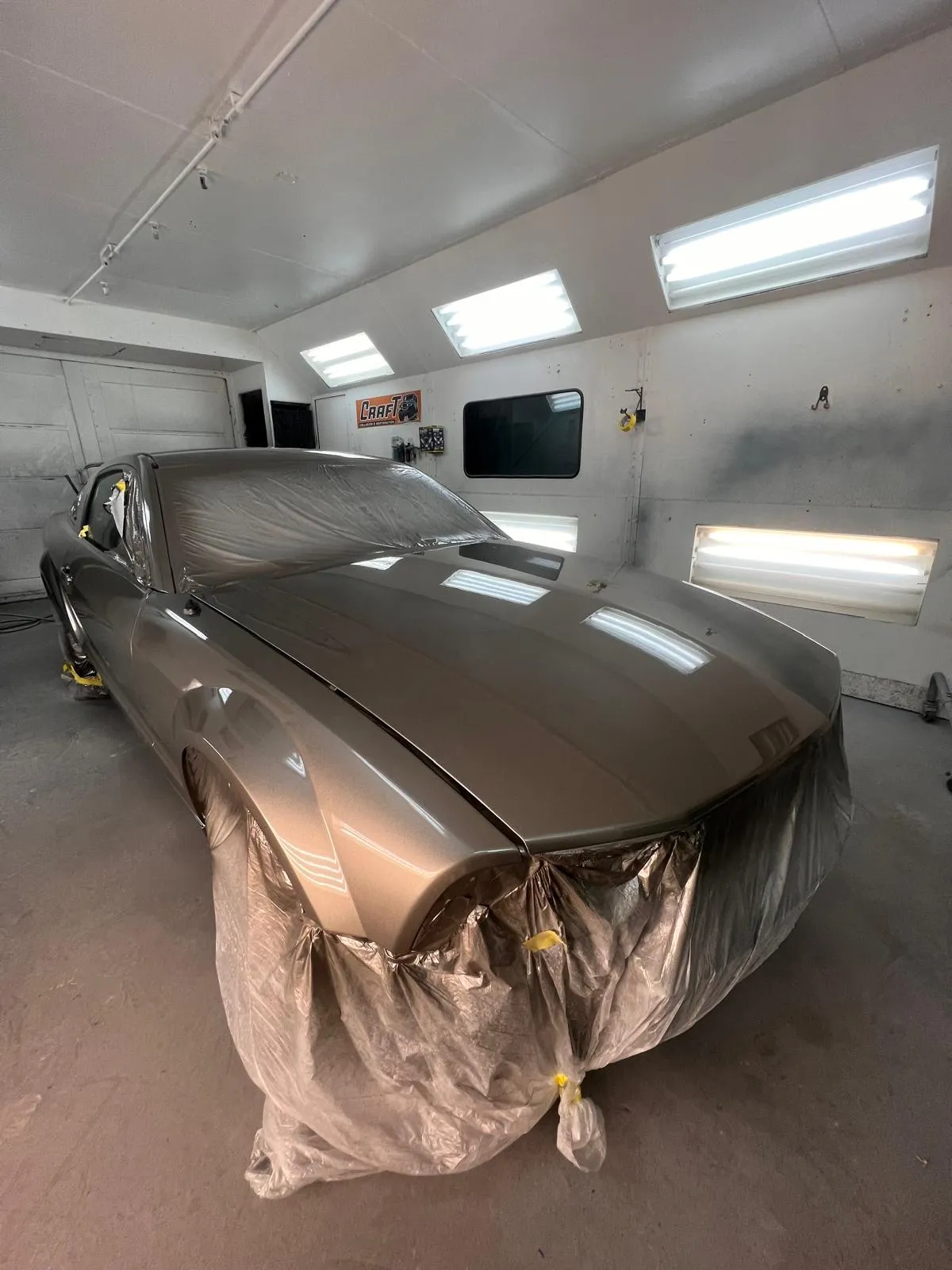 Champagne Ford Mustang GT masked and prepped for refinishing in the paint booth