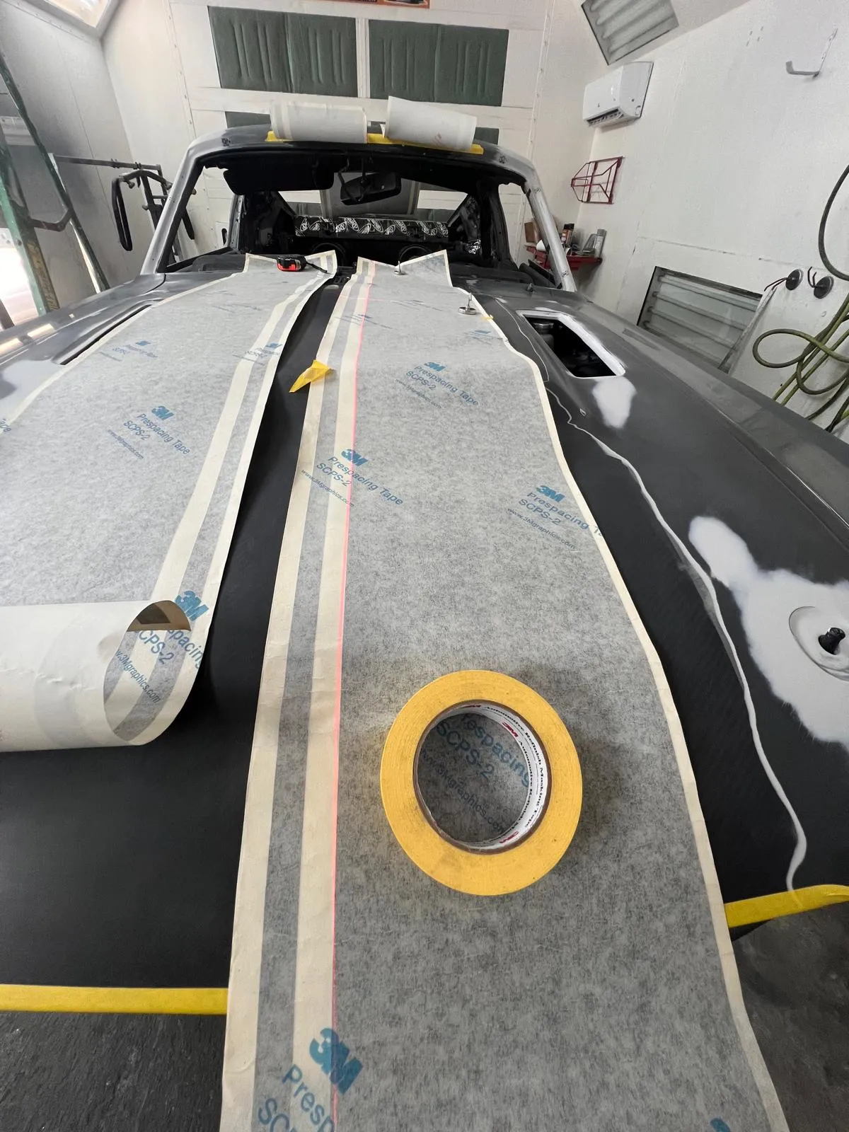 Masking tape laid out by hand along the hood to lay down custom racing stripes
