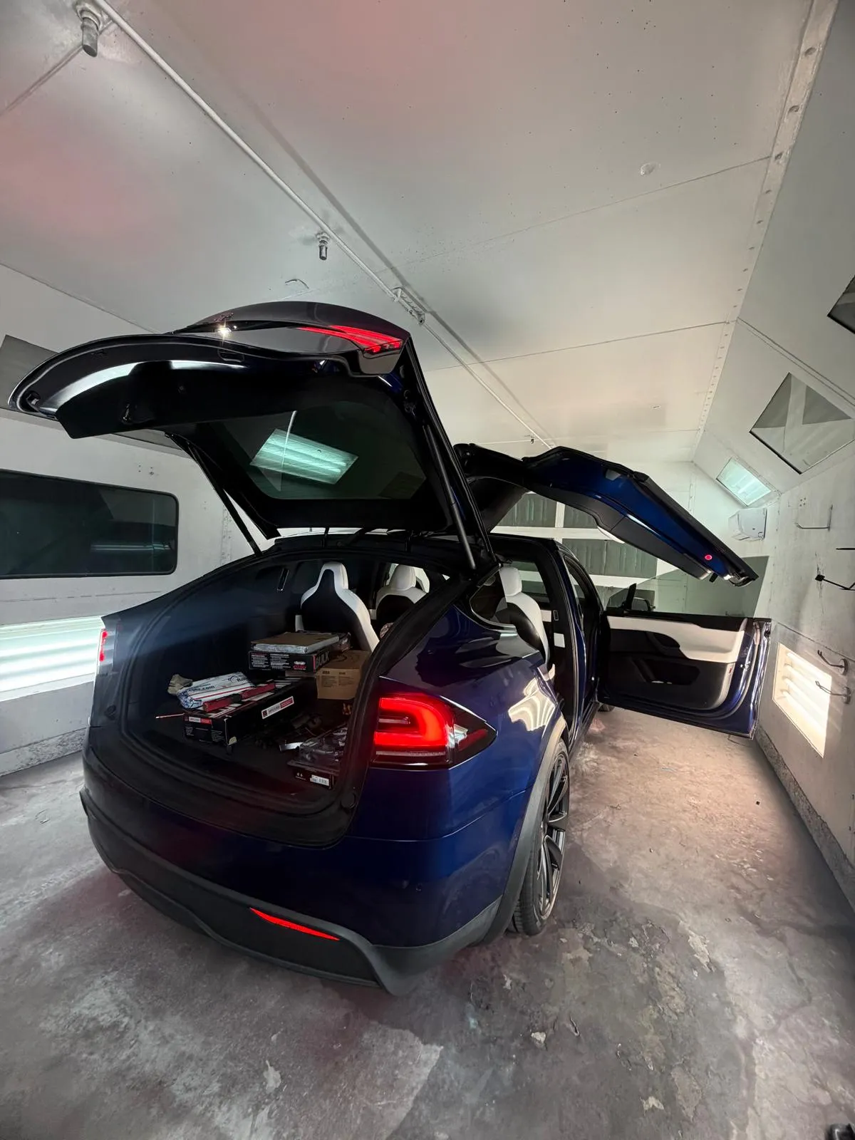 Tesla Model X with the falcon doors open inside the Craft Collision paint booth