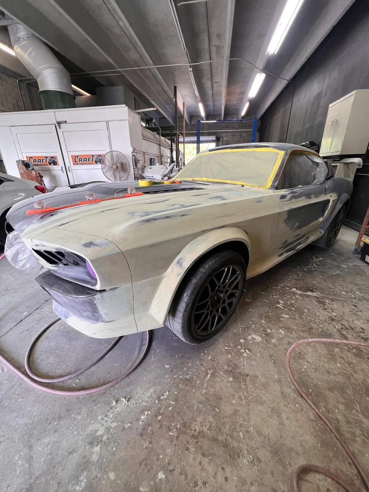 Widebody custom Mustang fastback in primer with black wheels mounted